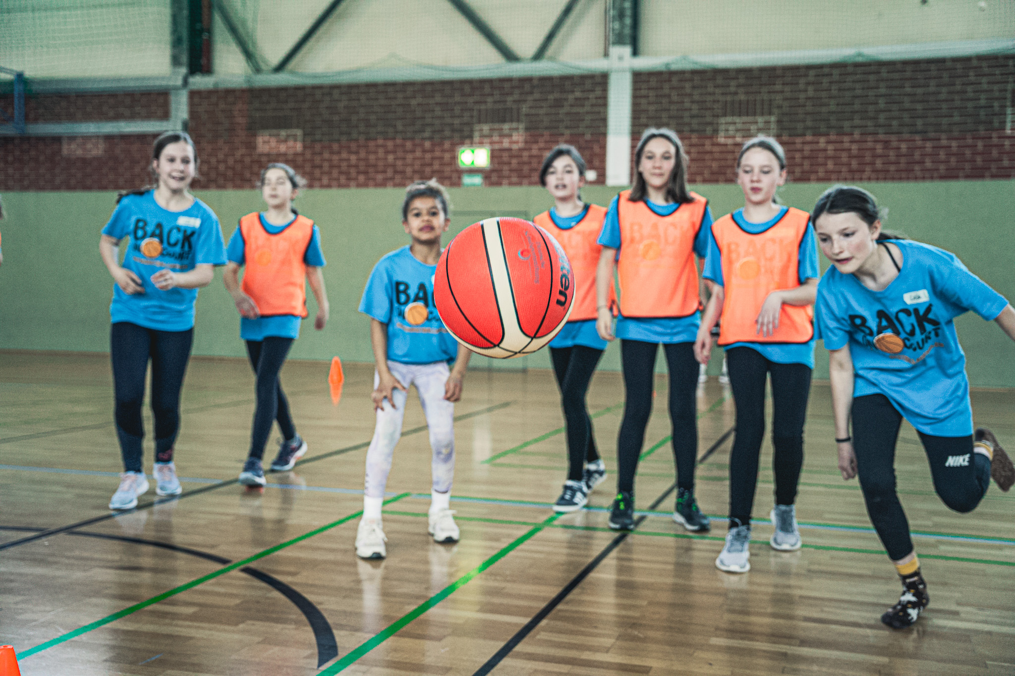 sieben Mädchen schauen einem Basketball hinterher