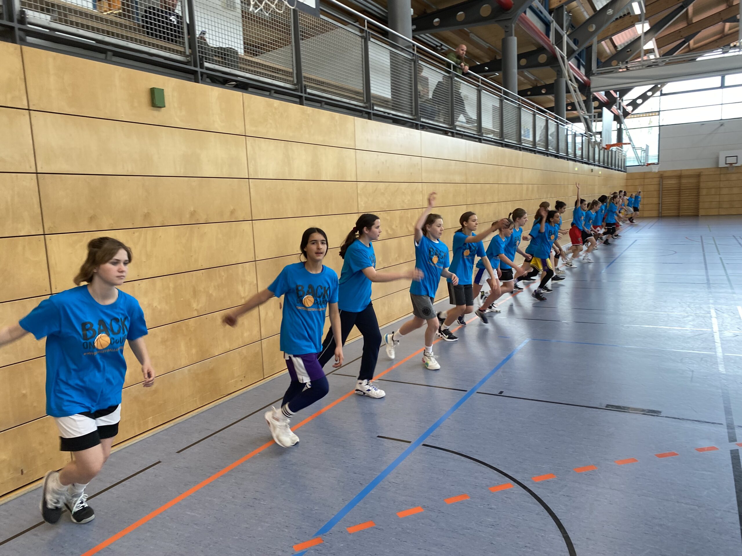 Gro´ße Mädchengruppe an der Baseline macht Laufschule