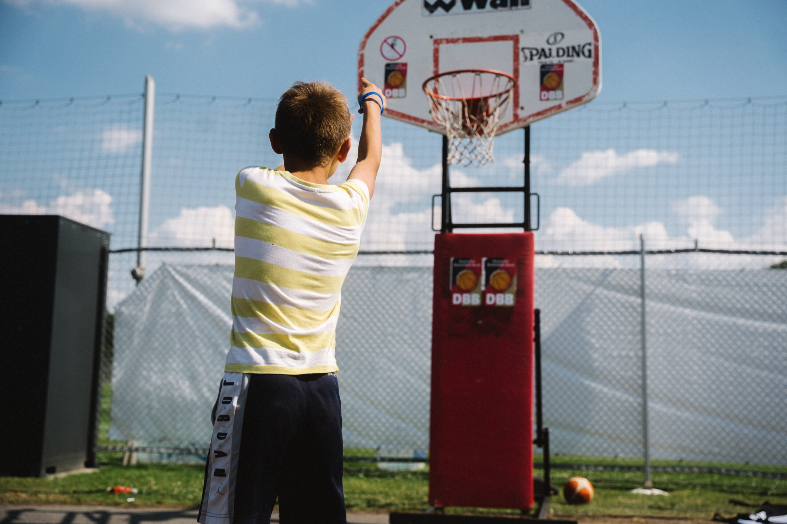 Junge in gestreiftem Shirt wirft auf Basketballkorb