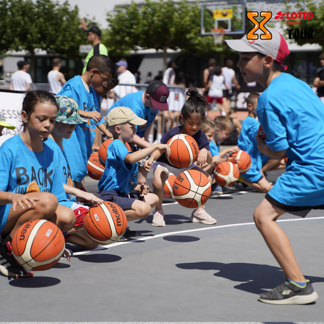 Jungen und Mädchen in blauen Shirts dribbeln Basketbälle tief am Boden