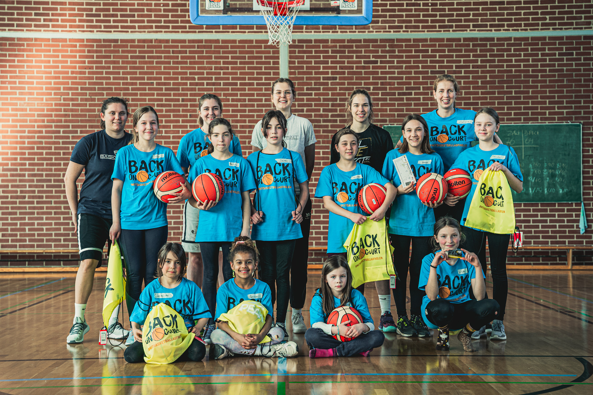 Gruppenbild Mädchen und Trainerinnen mit Basketbällen und Gymbags