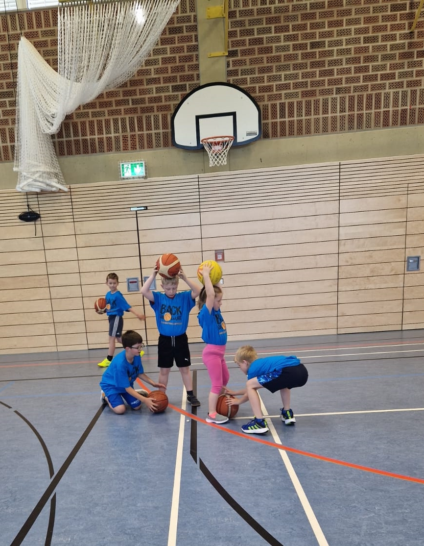 Vier Kinder spielen gemeinsam, rollen den Ball durch die Beine