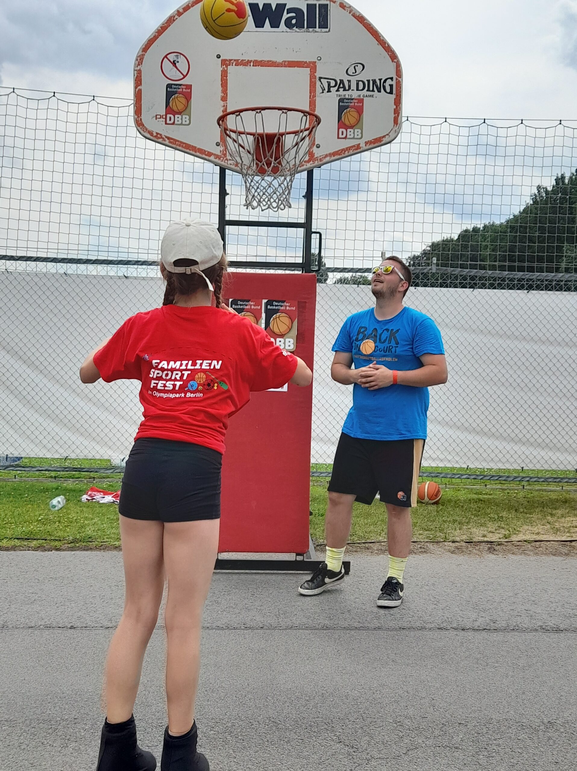 Mädchen auf Rollschuhen wirft auf Basketballkorb