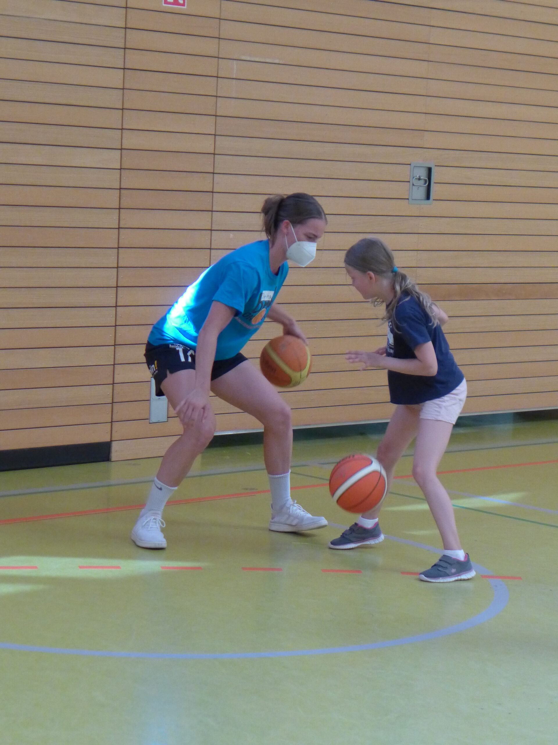 Trainerin zeigt Mädchen korrekte Ausführung beim Dribbeln