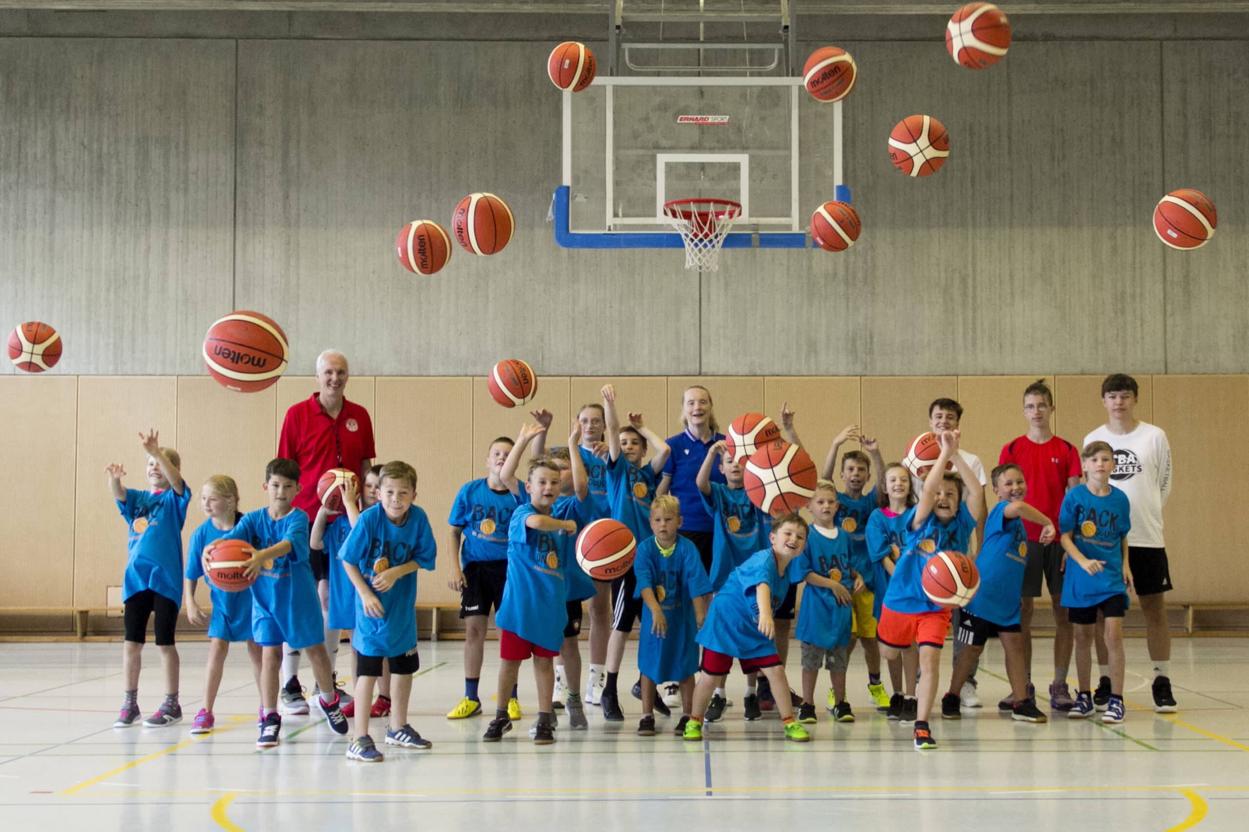 Kinder und Trainer*innen werfen Bälle Richtung Kamera