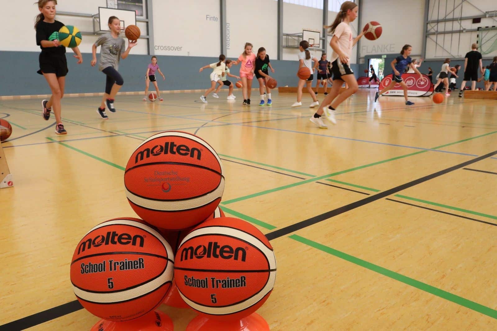 Basketbälle im Vordergrund, rennende Kinder im Hintergrund