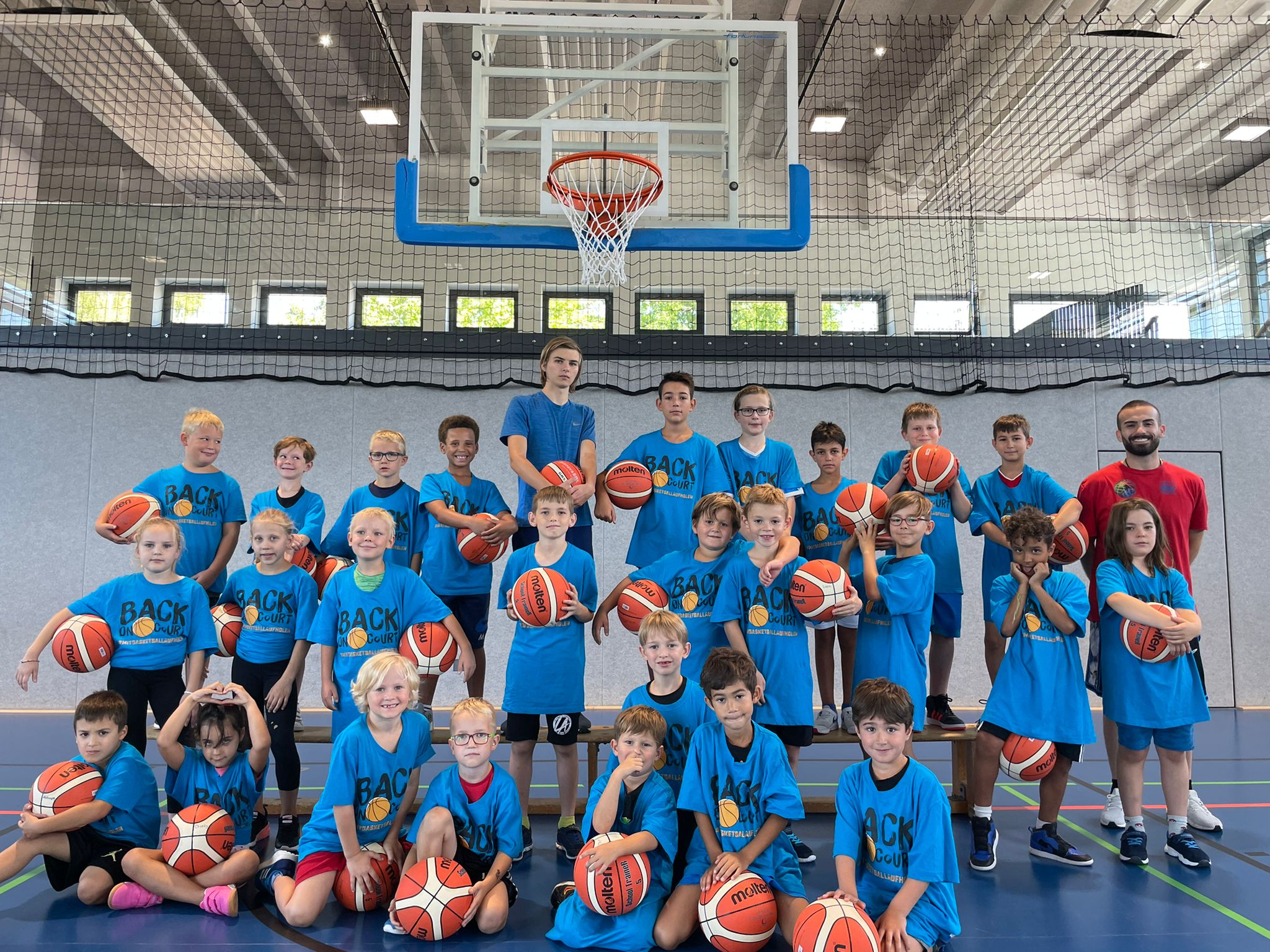 Gruppenbild Teilnehmer*innen und Trainer mit Basketbällen